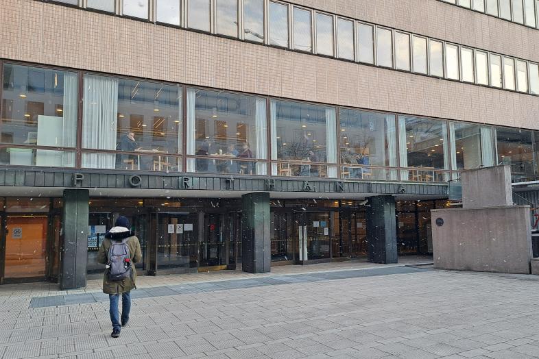 Opiskelija kävelee kohti Porthanian sisäänkäyntiä.