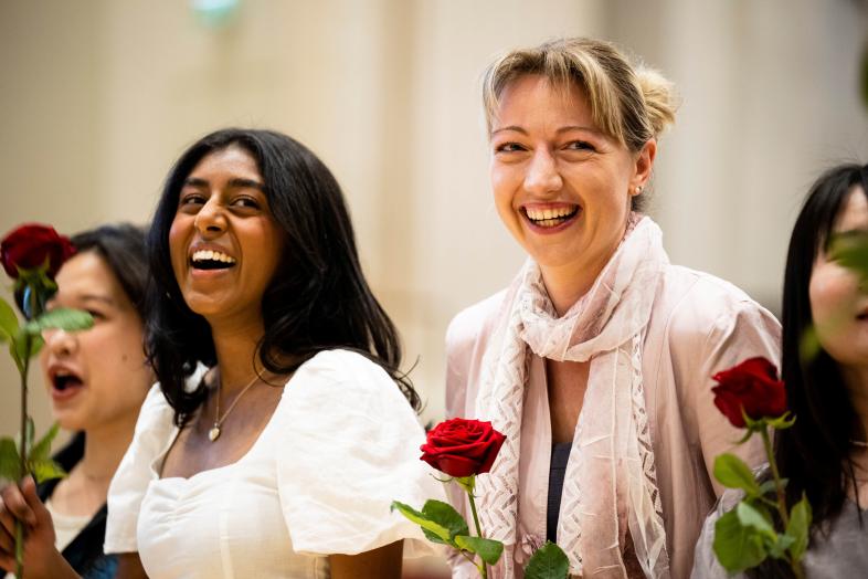 Nauravia juhlijoita ruusut kädessä.