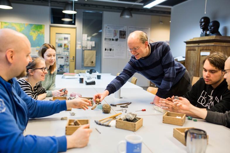 Opettaja ja ryhmä opiskelijoita työskentelee pöydän äärellä.
