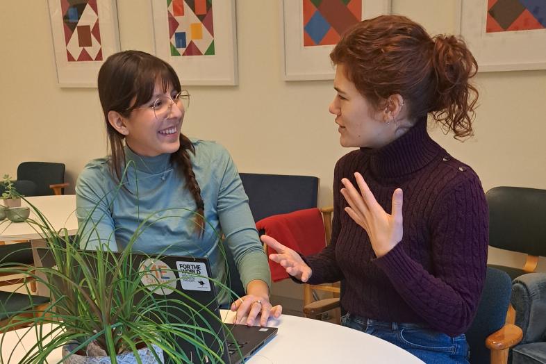 Kaksi opiskelijaa keskustelee kannettavan tietokoneen äärellä.