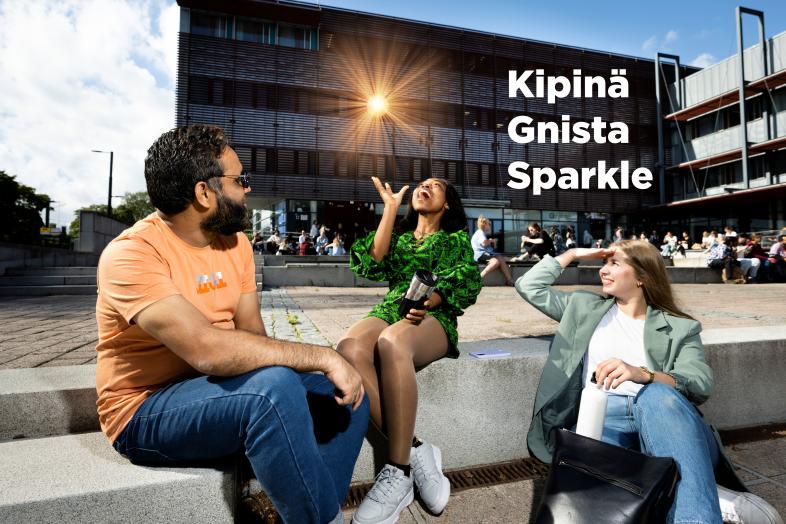 Kuvassa kolme henkilöä istumassa ulkona. Yksi henkilö heittää kimaltelevan pallon ilmaan. Kuvassa teksti kipinä, gnista, sparkle.