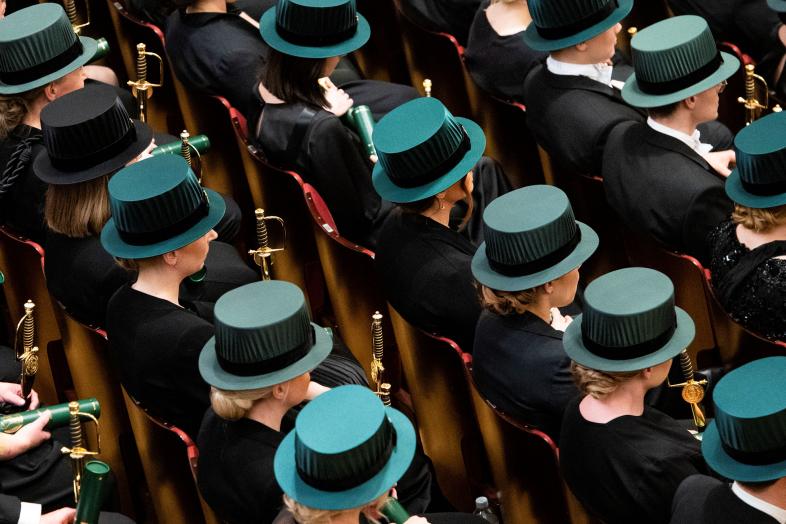 Promootioaktin osallistujia riveissä tohtorinhatut päässä.