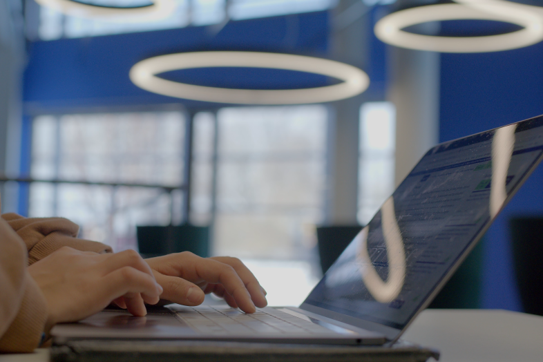 Kädet työskentelevät läppärin näppäimistöllä.