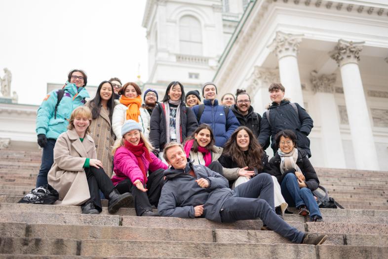 A group of students are smiling and posing on the steps in front of the cathedral