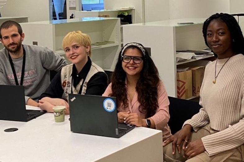A group of people sitting at a table with laptops
