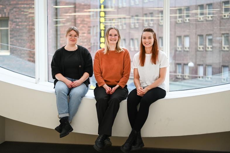 Three Mushketeersin kolmihenkinen tiimi istumassa Kaisa-talon ikkunan edustalla.