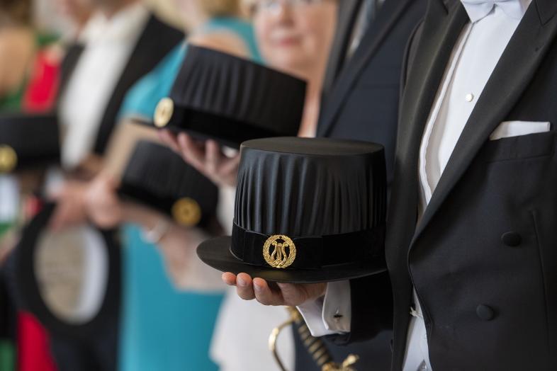 People holding doctoral hats in their hands.