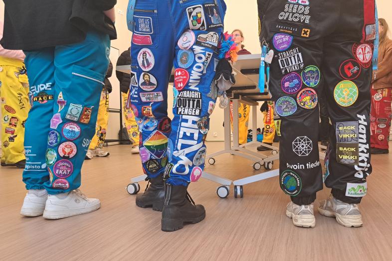 Students in student overalls in a lecture room.