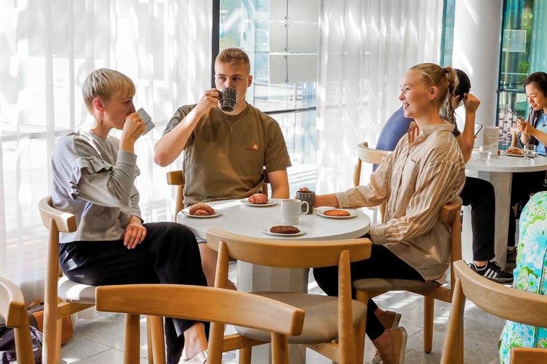 Kolme opiskelijaa kahvin ja pullan äärellä Porthanian UniCafessa.