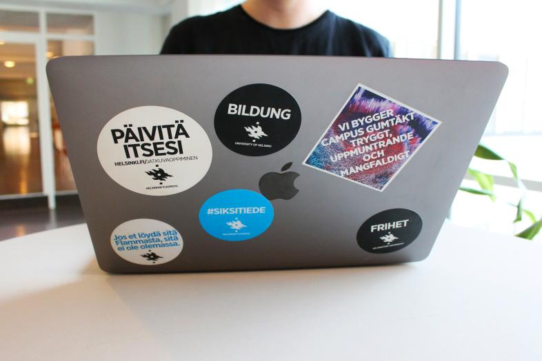 Avonainen läppäri, jossa kannessa tarroja.