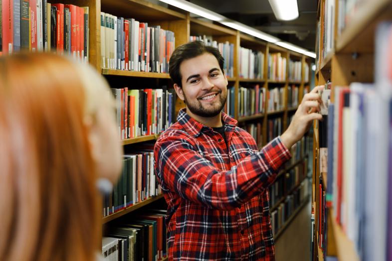 Kaksi henkilöä kirjahyllyjen välissä.