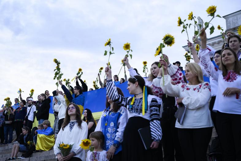 Ukrainalaiset kuorolaiset kohottavat auringonkukkia Tuomiokirkon portailla.