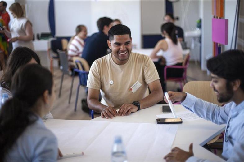 Group of people are sitting at a table smiling and working together