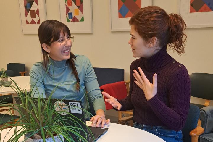 Kaksi opiskelijaa keskustelee pöydän ääressä.