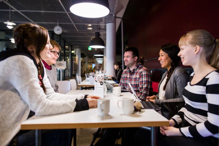 Ihmisiä keskustelemassa kahvipöydän äärellä.